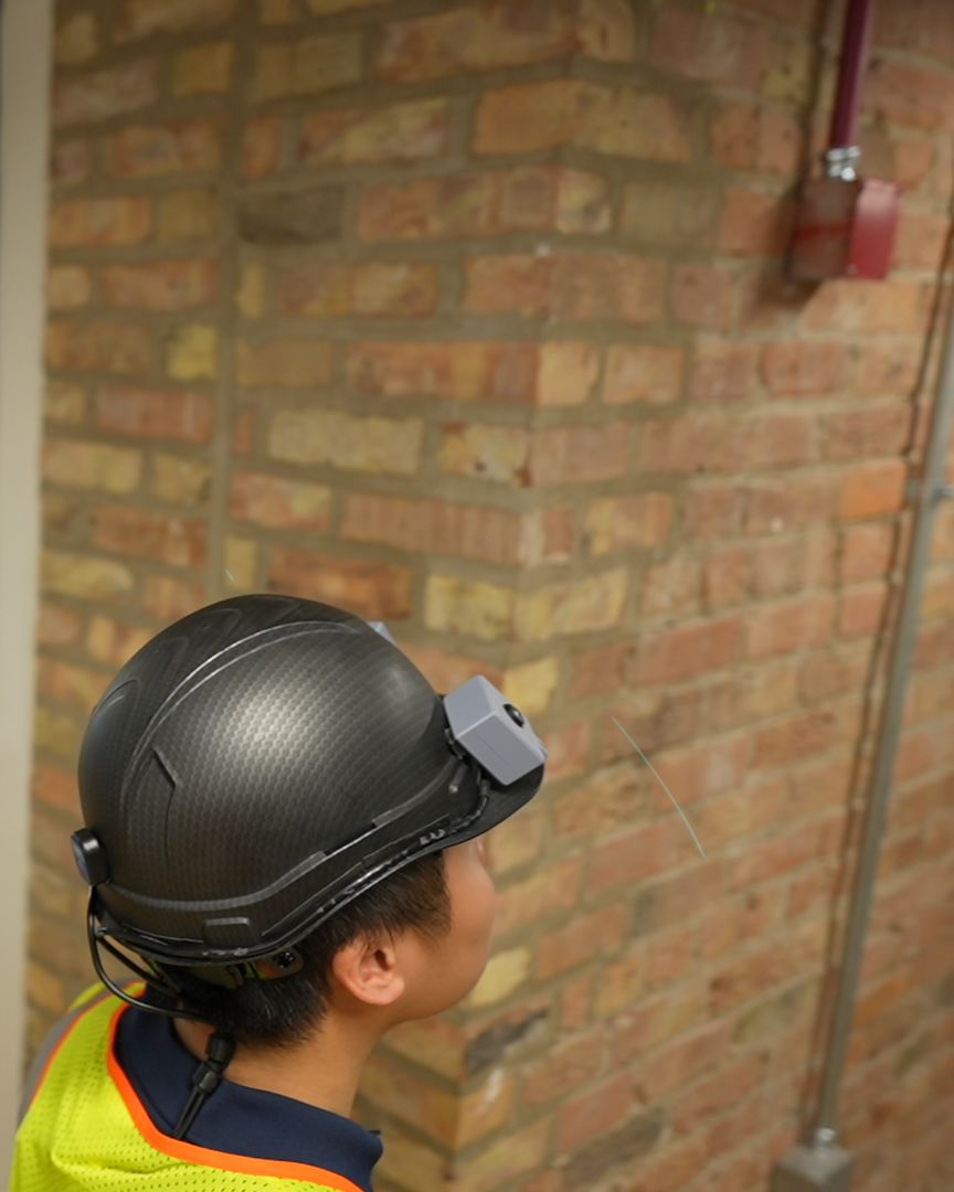 Side view of a worker wearing the helmet in a brick corridor